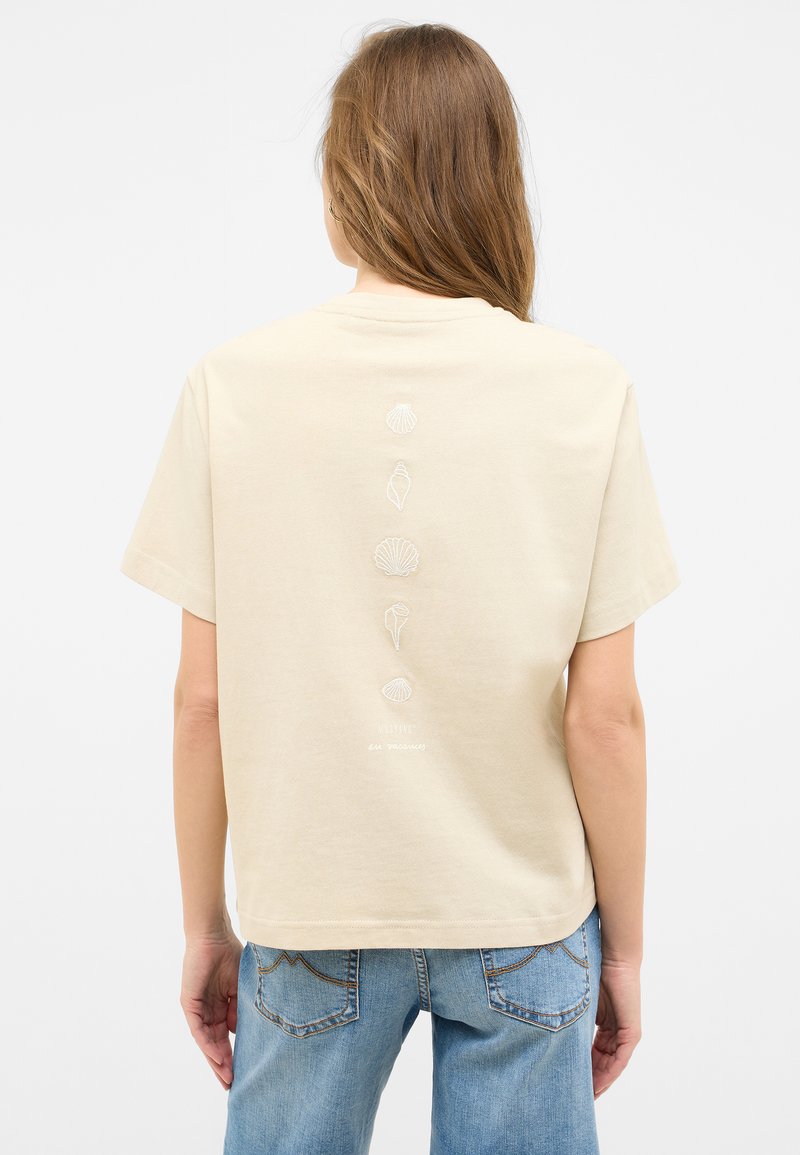 Beige cotton t-shirt with short sleeves, featuring white shell and sea creature embroidery down the back. Straight cut and casual fit.