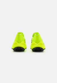Neon gule atletiske sko med sorte detaljer, der har et tekstureret materiale, polstret sål og et strømlinet design til støtte.