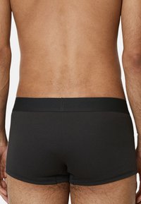Schwarze gerippte Herren-Boxershorts mit glattem elastischem Bund, tailliertem Design und minimalen Nähdetails.