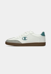 Hvit sneaker med en glatt skinnoverdel, grå semsket skinn detaljer, teal logo og en gummisåle med teksturert design.