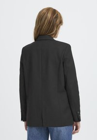 Črn blazer s prirejenim dizajnom, izreznimi kl collar-i in gumbnimi manšetami, z gladko teksturo in čistim, minimalističnim silhuetom.