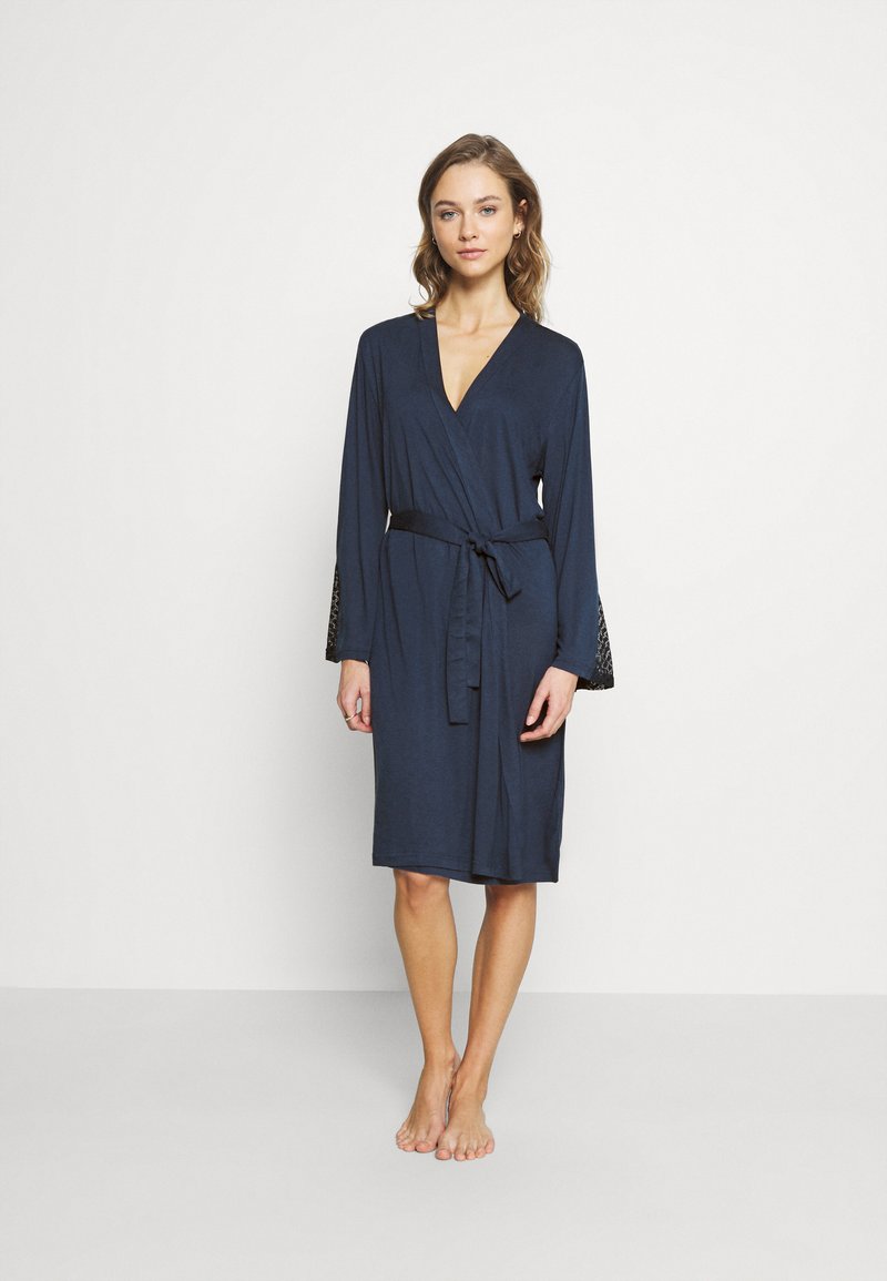 Marineblauwe wikkelrobe gemaakt van zachte stof, met lange mouwen met kantaccenten en een bijpassende strikceintuur, knielange ontwerp.