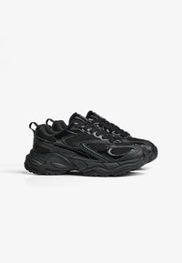 Čierne športové tenisky s vrchným materiálom z jemnej sieťoviny, zakrivenou gumovou podrážkou a textúrovanými detailmi. Obsahujú šnurovanie a zosilnenú pätu.