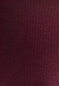 Burgundyribbad tyg med en strukturerad yta, som har vertikala linjer och en mjuk, tät väv. Lämplig för kläder eller stoppning.