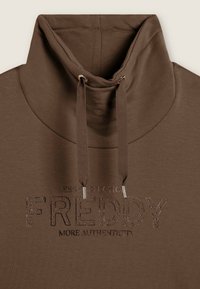 Sweatshirt en coton marron avec un col montant, dotée d'un cordon de serrage, d'une broderie de logo texturée et d'accents métalliques.