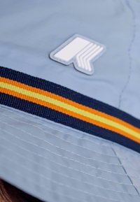 Light blue bucket hat featuring a thick navy band with orange and yellow stripes, and a white logo patch detailing on the front.