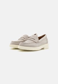Mocasini din suede bej cu pliuri frontale duble, accente brodate și o talpă din cauciuc crem, având un toc mic și un design tip slip-on.