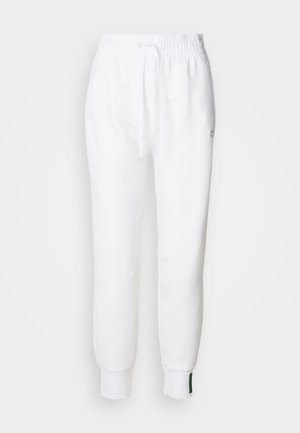 Pantalon de jogging blanc avec taille élastique et cordon de serrage, comportant des poches latérales et des poignets côtelés. Tissu doux avec un détail de logo brodé.