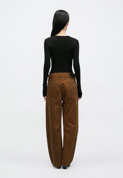 Top preto de manga comprida e calças largas com estampa de leopardo castanho, com acabamento texturizado e costuras visíveis, vistas por trás.