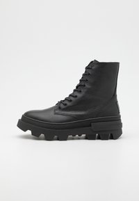 Bottes montantes noires en cuir texturé, avec des semelles en caoutchouc épaisses à motif dentelé et des lacets sur le devant.