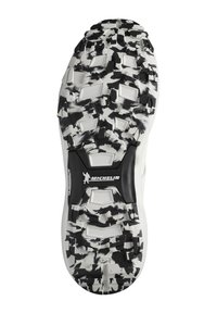 Semelle de chaussure de sport blanche avec un motif texturé en noir et gris, mettant en avant un logo Michelin proéminent au centre.