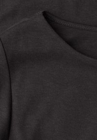 Zbliżenie na tkaninę ciemnoszarego swetra, charakteryzującą się miękkim, fakturowanym wykończeniem z szerokim dekoltem i widocznymi detalami szwów.