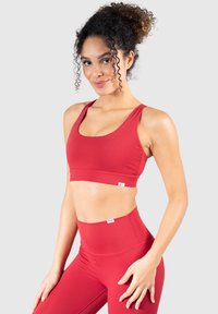 Sostenedor deportivo rojo y pantalones leggings de cintura alta hechos de tejido elástico. Presenta un escote redondeado y tirantes anchos, ofreciendo un ajuste ceñido.