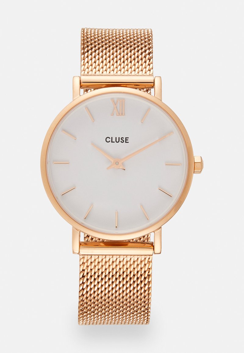 Cadran de montre blanc rond avec des index horaires dorés et le texte 'CLUSE'. Bracelet en maille dorée. Design minimaliste, finition métallique lisse, texture élégante.
