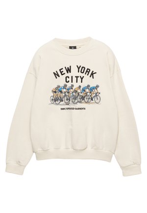 Kremna trenirka z napisom "NEW YORK CITY" nad grafiko kolesarjev na dirki in napisom "1991/UPDATED GARMENTS" spodaj.