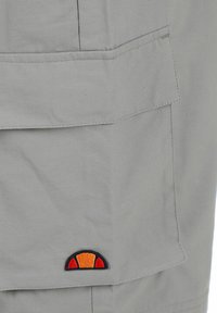 Light gray fabric with a square flap pocket featuring a small orange and red semicircle logo at the bottom corner.