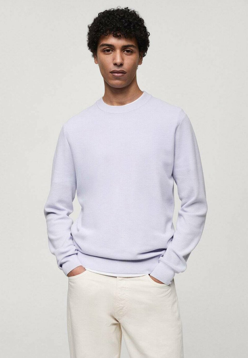 Pulover violet deschis confecționat dintr-un material texturat. Are un guler rotund și mâneci lungi, asortat cu pantaloni off-white.