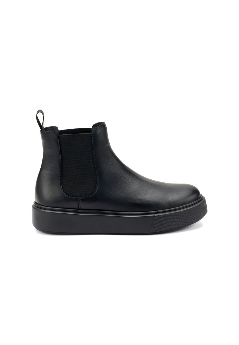 Botín de cuero negro con paneles laterales elásticos, puntera redonda y suela de goma gruesa. Presenta una tira en la parte trasera para facilitar su colocación.