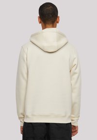 Cream-colored hoodie with a spacious hood, ribbed cuffs, and a waistband. Soft texture, minimal design, and no visible logos or patterns.