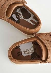 Bruna tygskor med slip-on-design, som har en flätad rem, en vadderad innersula med leopardmönster och en vit gummisula.