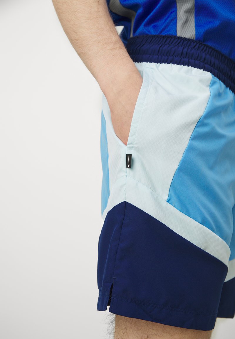Pantaloni sportivi da uomo con un design a strati, con pannelli blu chiaro e navy, tasche laterali e un'etichetta in tessuto sulla cucitura.