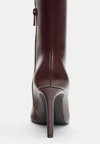 Gheata de gleznă din piele burgundy închis cu partea superioară ajustată, vârf ascuțit, toc stiletto înalt și detalii cu fermoar lateral. Textură netedă.