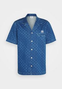Chemise en denim à manches courtes avec un motif géométrique bleu, un col à revers, une poche avant et un logo adidas blanc sur la poitrine.