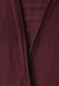 Bordeaux brei stof met een V-halslijn. Heeft een geribbelde textuur en zichtbare stiksels langs de randen.