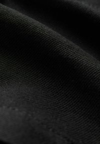 Schwarzer gewebter Stoff mit glatter Textur, der ein dezentes diagonales Muster und feine Nähdetails zeigt. Der Stoff ist weich und geschmeidig.
