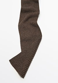 Calza a coste marrone in maglione distesa con leggere pieghe, che mostra il tessuto di lana testurizzato su uno sfondo bianco.