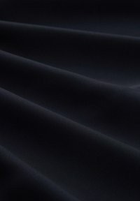 Un tissu noir texturé se drape en vagues, révélant une surface lisse avec des côtes horizontales fines, idéal pour diverses applications textiles.
