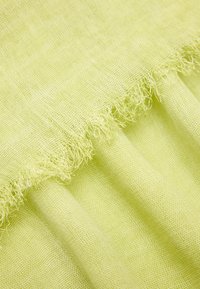 Lniana tkanina w jasnozielonym kolorze o przezroczystej teksturze, z postrzępionymi krawędziami i luźnym, swobodnym wyglądem.