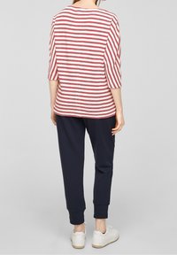 Rood en wit gestreepte top met 3/4 mouwen, gecombineerd met marineblauwe broek. De outfit heeft een Relaxed fit en een casual ontwerp. Witte sneakers maken de look compleet.