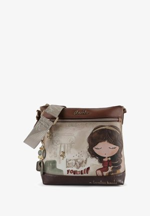 Braune Leder-Umhängetasche mit cremefarbenem Vorderteil, das ein Cartoon-Mädchen, den Text "Kiss Yourself" und dekorative Charm-Anhänger zeigt.