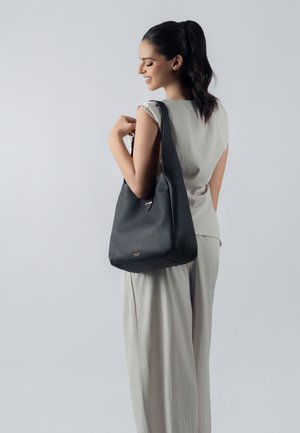 Black textured leather shoulder bag with a single strap, featuring a subtle gold accent and a soft, rounded shape.