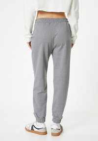 Grijze sweatpants met een elastische tailleband en enkelmanchetten. Gemaakt van zachte stof, met een relaxed fit. Gemaakt in combinatie met witte sneakers.