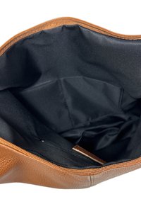 Hnědá kožená taška otevřená, aby ukázala prostorný černý látkový interiér s malou zipovou kapsou na jedné straně.