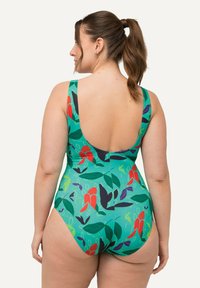 Maillot de bain une pièce avec une base verte vibrante ornée de motifs floraux rouges et violets, de bretelles larges et d'un décolleté plongeant dans le dos.