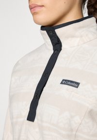 Fleece pullover in crème met een geometrisch patroon, voorzien van een zwarte drukknopenlijst en het Columbia-logo op de borst.