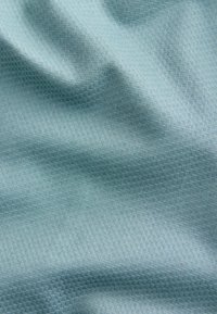 Tissu bleu clair avec un motif texturé subtil et des plis doux créant des ombres et des reflets sur la surface.