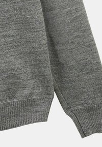 Pull en maille gris avec une finition texturée, des poignets côtelés et un design avec fentes latérales pour faciliter le mouvement.