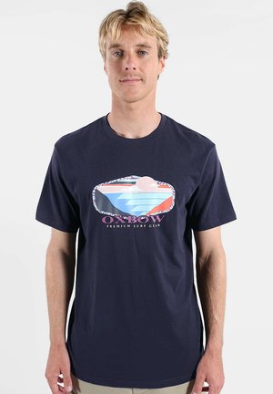 T-shirt bleu marine en coton doux, arborant un graphisme coloré avec des éléments d'eau et de soleil, et portant le texte "OXBOW Premium Surf Gear".
