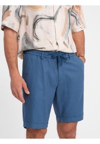 Shorts bleus avec une taille élastique, un cordon de serrage et des poignets roulés. Fabriqués en tissu léger, offrant une texture lisse.