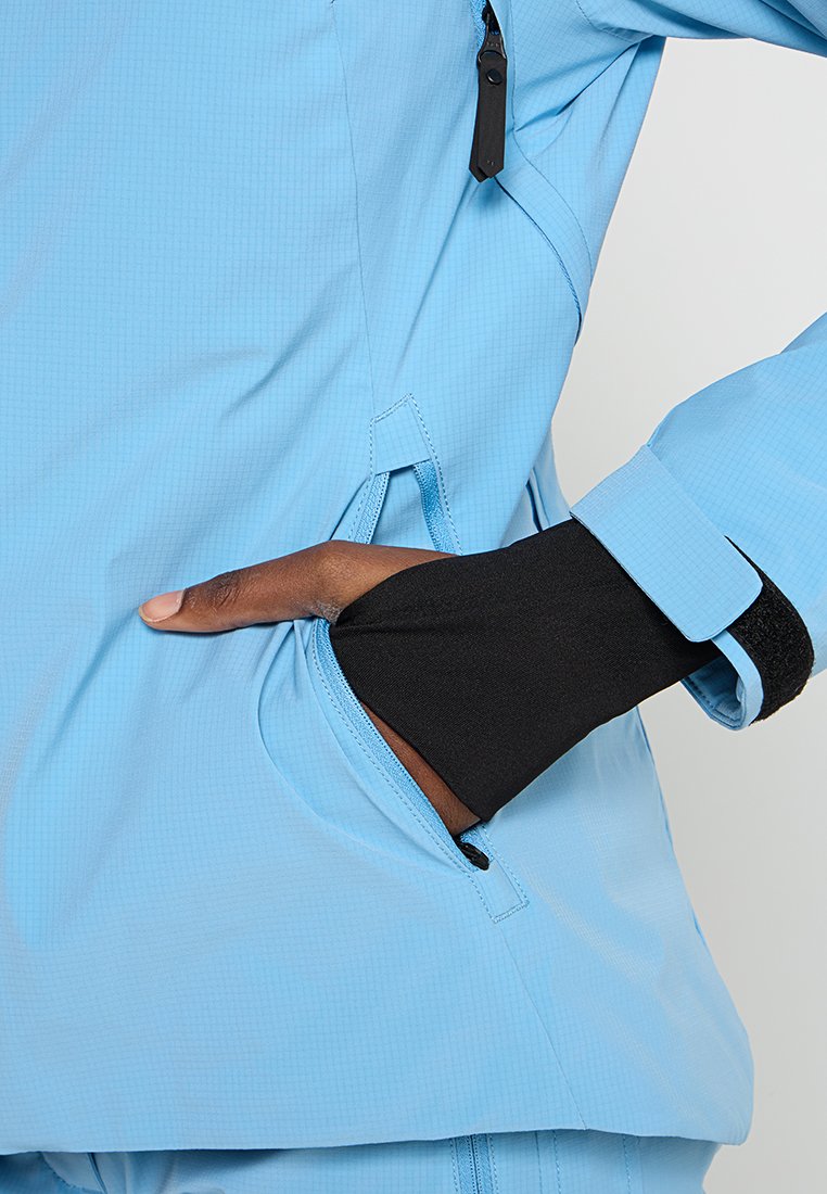 Jasnoniebieska kurtka o teksturowym wykończeniu, z zamykaną kieszenią i czarnymi mankietami wewnętrznymi dla większego komfortu cieplnego. Kieszenie umiejscowione na wysokości talii.