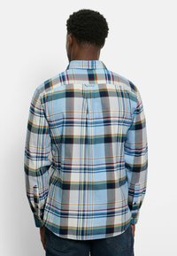 Karierte Hemd in Blau, Weiß, Rot und Grün. Verfügt über lange Ärmel, Knopfmanschetten und einen Rückenfalte für Struktur.