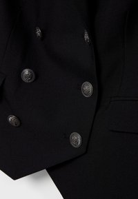 Schwarzer, doppelt geknöpfter Blazer mit sechs dekorativen silbernen Knöpfen und einer Klappentasche auf der rechten Seite.