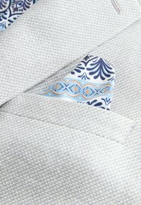 Svetlosivá textúrovaná sako s vreckom a zloženou vreckovkou s modrými, námorníckymi a oranžovými zložitými vzormi.