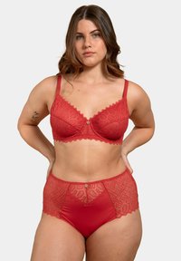 Ensemble de soutien-gorge en dentelle rouge et de culottes taille haute avec des bords festonnés et des motifs géométriques, comportant un bouton décoratif au centre.