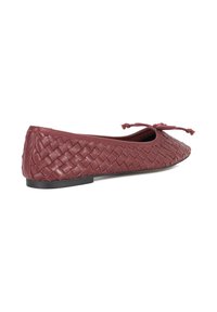 Ballet flat in burgundy leather with a woven pattern. Features a rounded toe and a bow accent on the front. Flat black sole.