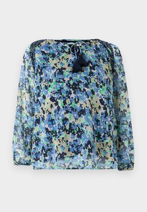 Blouse transparente avec un motif floral bleu, vert et noir, col rond avec cordon de serrage et deux pompons. Manches longues et amples.